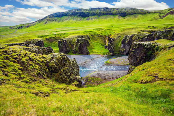 Fast river with glacial water flowing among cliffs, Fyadrarglyufur, Iceland.