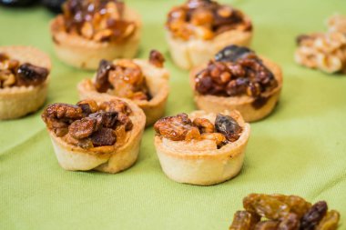 Pişirme profesyonel. Arka plan - yeşil. Küçük alakart tartı kek fındık ve kuru meyve dolgulu