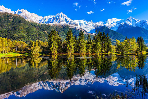 Fantastic sunset in the Alps. Snowy peaks of the Alps are reflected in the lake in mountain resort of Chamonix. The foot of Mont Blanc. Concept of active and ecotourism