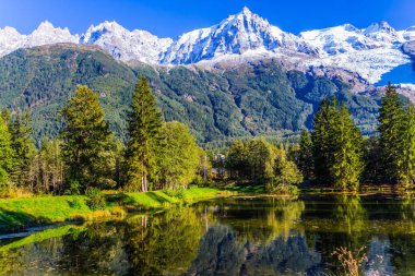Şehir - Park günbatımında aydınlatılır. Chamonix - Mont Blanc dağ tatil. Göl herdem yeşil çam ve karla kaplı Alpler yansıtıyordu. Aktif ve ekolojik turizm kavramı