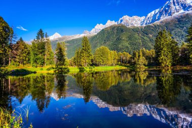 Concept of active and ecotourism. Fantastic sunset in the autumnal Alps. Stunning reflections of snowy peaks in the lake water. Mountain resort of Chamonix, the foot of Mont Blanc clipart