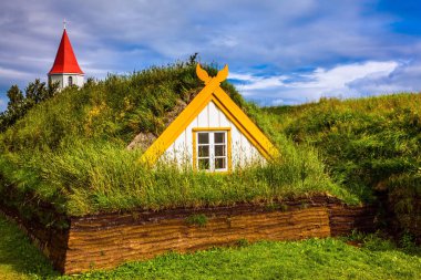 Köy evlerinin çim ve çim kaplı. Kırmızı çatılı çatı ile kilise çan kulesi. Etnografik Müzesi-Emlak Glaumbaer, İzlanda. Tarihi ve kültürel Turizm kavramı