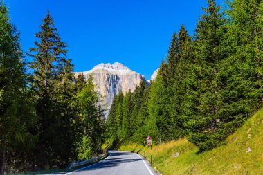 Güney kireçtaşı Alps. Güzel bir güneşli gün. Kalker ve dolomit kayaları dibinde iğne yapraklı ormanlarda yol geçmektedir. Etkin, aşırı ve araba Turizm kavramı 