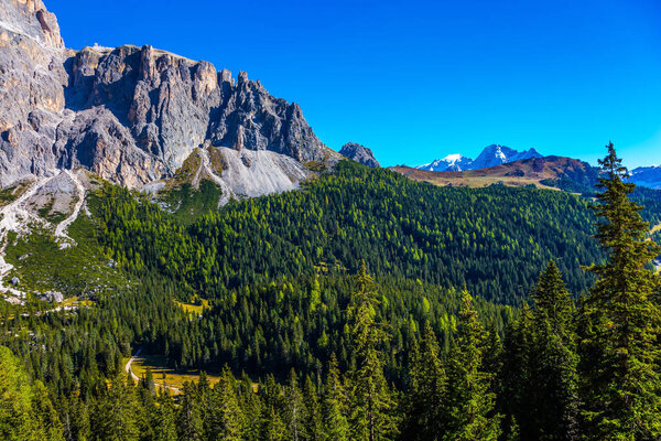 Most beautiful route in the Italian Dolomites. Majestic white and gray rocks against the blue sky. The coniferous forests. The concept of active and car tourism 