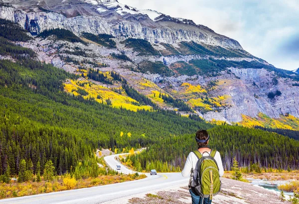 The grandiose nature of the Rockies of Canada. Experienced woman -  tourist with a backpack is standing by the road 93 \