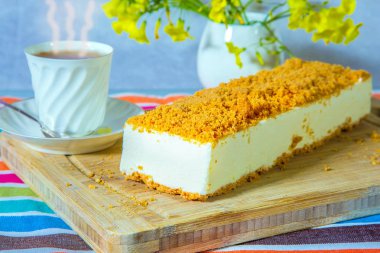 Beyaz peynirli kek, turuncu tatlı kırıntıları ile serpilir.