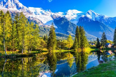  Göl herdem yeşil çam ve karla kaplı Alps yansıyan. 