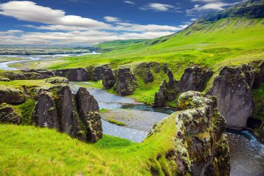  Kayalıklarla tuhaf şekli çevreleyen akışı buzul su ile. İzlanda'daki çarpıcı Kanyon