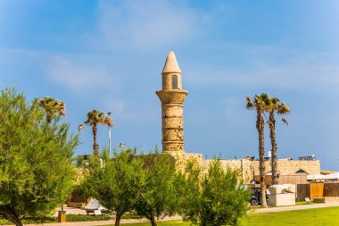 Caesarea eski bağlantı noktası. Geri yüklenen minare yeşil çim çim ve dekoratif acacias çevrilidir. İsrail'e seyahat. Arkeolojik ve tarihsel turizm kavramı
