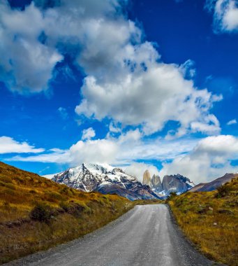 Otomobil aşırı Turizm kavramı. Torres del Paine Millî Parkı çakıl yolda. Dağlar ve kayalar Torres kar ve buz ile kaplıdır 
