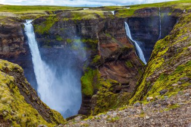 Yüksek şelale Hayfoss pitoresk ve tehlikeli tundra kanyon. İzlanda'daki bulutlu ve rüzgarlı yaz günü. Aşırı ve phototourism kavramı