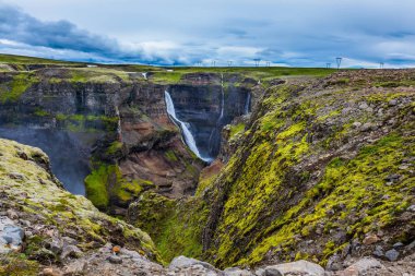  Yüksek şelale Hayfoss pitoresk ve tehlikeli tundra kanyon. Aşırı ve phototourism kavramı. İzlanda'daki bulutlu ve rüzgarlı yaz gün
