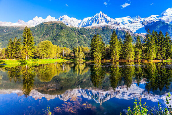 Magically beautiful park in the mountain resort of Chamonix, at the foot of Mont Blanc. Snowy peaks of the Alps are beautifully reflected in the lake. Concept of active and ecotourism