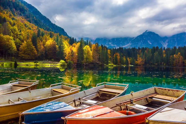 Boat station on the picturesque quiet lake of Lago de Fusine. The beautiful multu-colored forests in the mountain Alpine valley. Concept of cultural and ecological tourism