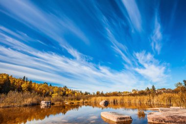 Indian summer in Manitoba, Canada. Cirrus clouds reflecting in Winnipeg River. Old Pinawa Dam Park.  clipart