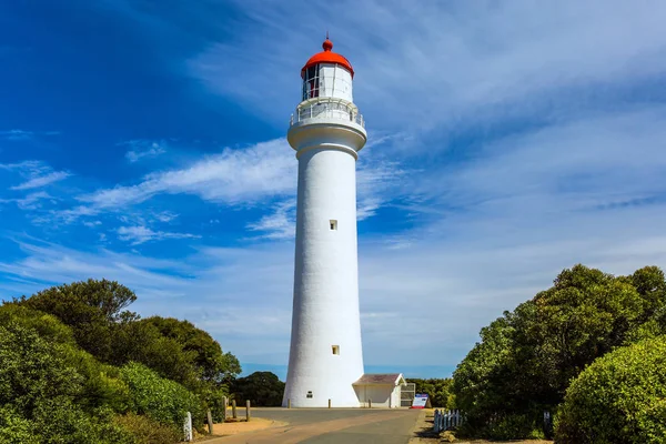 Australia. The Great Ocean Road running along Pacific coast. Picturesque white lighthouse with red roof.