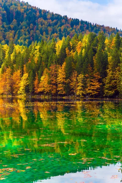 Flood after rain. The quiet lake in Northern Italy, Lago de Fusine. Scenic reflections of multicolored forests in the smooth water of the lake. Concept of cultural and ecological tourism