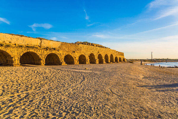 Закат солнца на средиземноморском побережье в Цесареа. "Высокий" акведук, построенный во времена правления Ирода Великого. Концепция активного, экологического и исторического туризма
