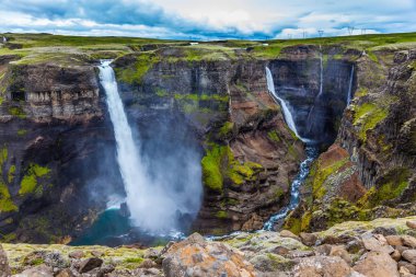  Yüksek şelale Hayfoss tehlikeli tundra kanyon. Aşırı ve phototourism kavramı. İzlanda'daki bulutlu ve rüzgarlı yaz gün