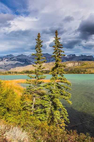 Concept of active and ecological tourism.  Rocks and lakes under flying clouds. Cloudy Indian summer in the Rockies of Canada