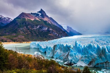 Petagonya Lago Argentino gölünün üzerinde devasa buzul Perito Moreno. Santa Cruz Arjantin il. Bulutlu gökyüzü ufuk kapsar. Aktif ve ekolojik turizm kavramı