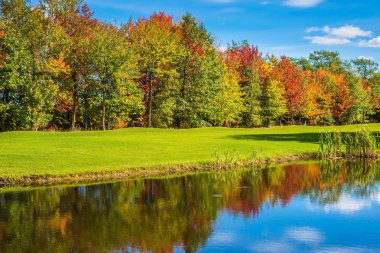 Kırmızı ve sarı sonbahar yaprakları göl temiz su yansıtıyordu. Eğlence Turizm kavramı. Park fantastik güzellik. Güneşli bir gün Fransız Kanada'da parlayan