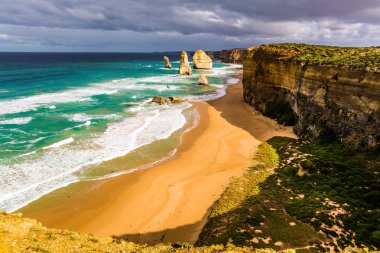 The concept of active and phototourism. Morning light on the Pacific coast near Melbourne. Famous rocks Twelve Apostles in ocean waves surf clipart