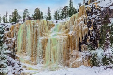 Donmuş su duvarı. Donmuş şelale çok renkli buz sarkıtları picturesquely dik bir uçurumdan düşmek. Lapland. Fotoğraf ve eko-turizm kavramı