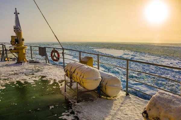 Dim sun in Lapland. The concept of active and extreme tourism. The strip of ice crumb spreads behind the icebreaker. The excursion to the arctic tourist cruise on the sea icebound