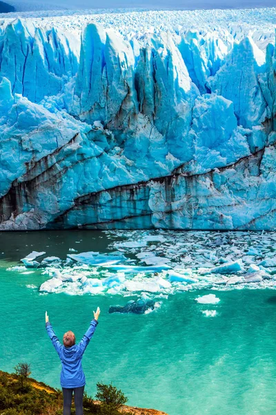 Kadın mavi bir buz duvarının önünde duruyor. — Stok fotoğraf