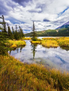 Bulutlu gökyüzü güzel bir şekilde göle yansıyor. Aktif ve ekolojik turizm kavramı. Kanada 'nın Rocky Dağları' nda muhteşem bir yolculuk