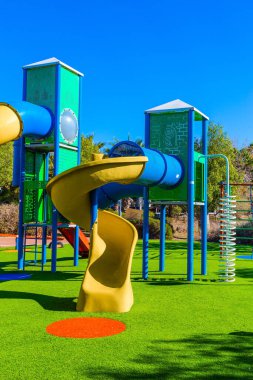 Çocuklar için açık güneş çimleri. Değişik renklerde eğlencelerle dolu güvenli ve rahat çocuk parkı. Parlak, güneşli bir sabah. Çocukların fiziksel ve zihinsel gelişimi kavramı