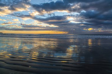 Hafif rüzgar suda küçük dalgalanmalara neden olur. Yeni Zelanda, Pasifik Sahili. Günaydın, sakin. Yumuşak bulut renkleri okyanus suyuna yansıyor. Sanatsal fotoğrafçılık kavramı