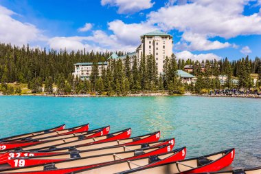 Turistler için kırmızı kanolar kıyıya demirlidir. Louise Gölü - gök mavisi suyla çevrili göl ormanlarla çevrilidir. Rocky Dağları. Ekolojik, aktif ve fotoğraf turizmi kavramı