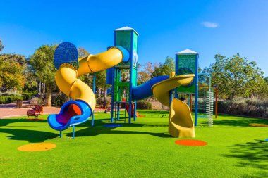 Çocuklar için açık güneş çimleri. Parlak, güneşli bir sabah. Değişik renklerde eğlencelerle dolu güvenli ve rahat çocuk parkı. Çocukların fiziksel ve zihinsel gelişimi kavramı