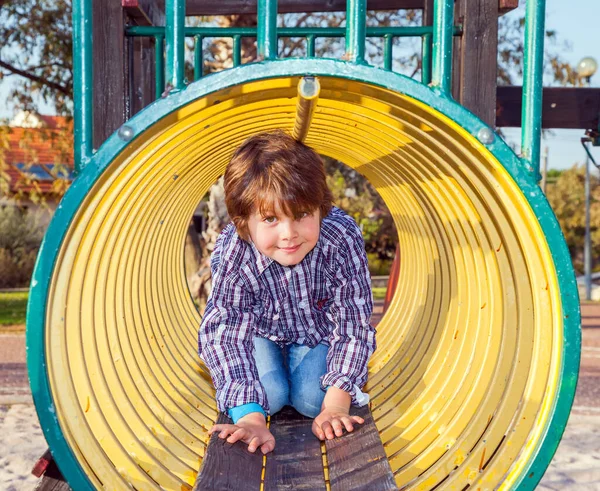 子供の遊び場 パイプの通路に沿って小声でチャーミングなカウボーイの少年がクロールします 天気のいい日だ 写真広告と幸せな子供時代の概念 — ストック写真