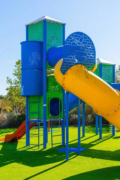 Safe and cosy children \'s playground with a variety of multicolored attractions. Open sun lawn for kids. Bright warm sunny morning. Concept of physical and mental development of children