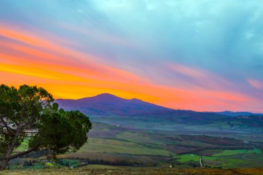 Gökyüzünün kenarı pembeye döner. Güneş doğuyor. Gün doğumunda inanılmaz bulutlar. Valley, Pienza şehrinin etrafındaki koruyucu bir duvardan çekilmiş. Aktif ve fotoğraf turizmi kavramı