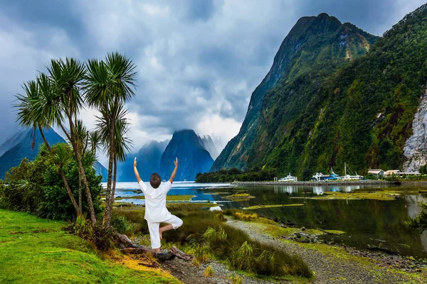 密尔福德湾峡湾的草甸海岸长满了茂密的草丛 穿着白色西服的老年妇女做瑜伽 新西兰 游艇和船只的港口 积极和摄影旅游的概念 — 图库照片