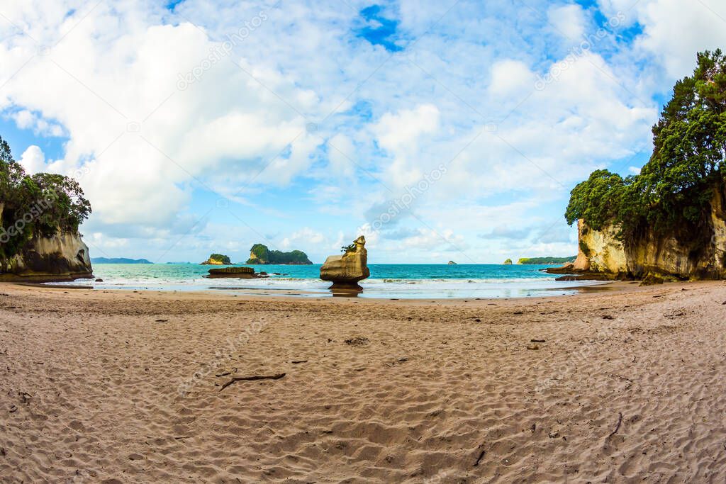 Picturesque boulders and rocks on a sandy beach. New Zealand. Cathedral Cove on Coromandel Peninsula at sunset. The evening tide begins. The concept of exotic, ecological and photo tourism