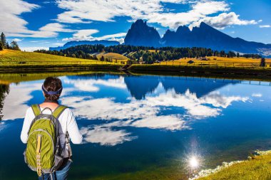 Dolomitlerde Kızılderili yazı. Alpe di Siusi, İtalya 'nın Dolomitler şehrinde büyüleyici bir platodur. Yeşil sırt çantalı ince kadın güzel manzaraya hayran. Yürüme, ekolojik ve fotoğraf turizmi kavramı