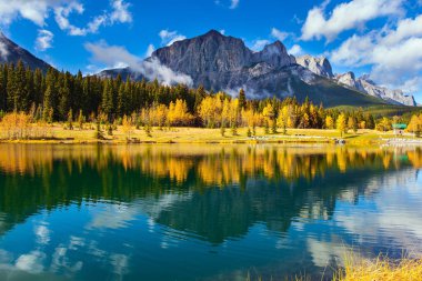 Kanada Kayalıkları. Banff Park 'taki Canmore şehri. Parlak sonbahar ormanı gölün yumuşak suyuna yansıyor. Aktif, ekolojik ve fotoğraf turizmi kavramı