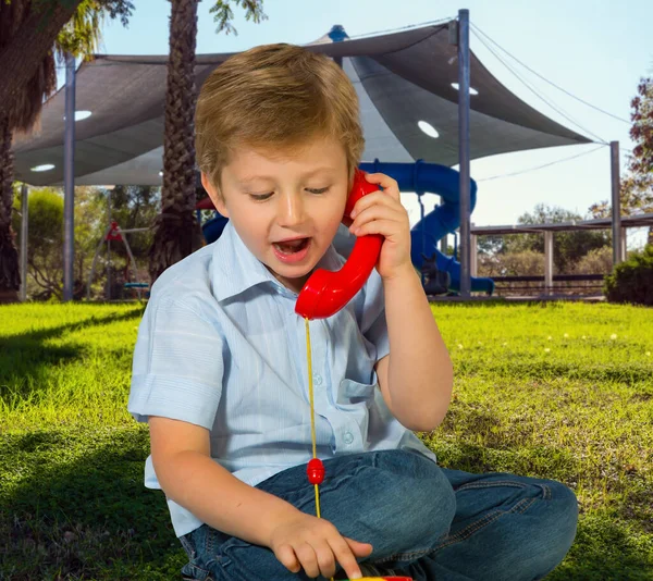 Charmante Blonde Jongen Spreekt Een Rode Telefoon Gezellige Veilige Kinderspeelplaats — Stockfoto