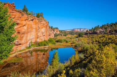 Küçük su birikintisi kayaları yansıtır. Büyük kırmızı kumtaşı yamaçları. Paria Kanyonu-Vermilion Uçurumları Vahşi Doğa Bölgesi. Arizona, Utah. ABD. Aktif, aşırı ve fotoğraf turizmi kavramı