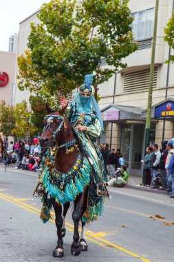 SAN FRANCISCO, ABD - 11 Ekim 2009 Kolomb Günü. Ulusal bayramın onuruna binicilik geçit töreni. Doğulu süslü elbiseli bir kadın bakımlı atlara biniyor..