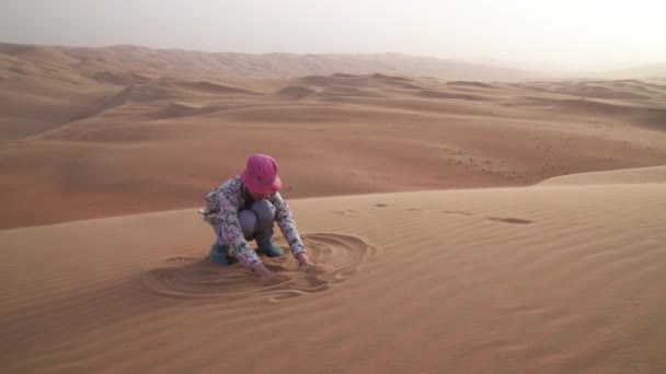 Teenager ragazza dipinge sulla sabbia in Rub al Khali deserto magazzino filmati video — Video Stock