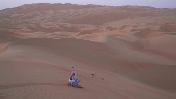 Teenage girl rotola sulla lavagna sul pendio di una duna nel deserto di Rub al Khali Emirati Arabi Uniti stock footage video — Video Stock