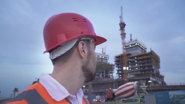 Людина в шоломі, архітектор, інженер, менеджер розповідає про хід будівництва у вечірньому відео — стокове відео
