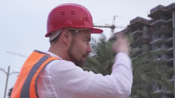 Man in een helm, architect, ingenieur, manager vertelt over de voortgang van de bouw in avond stock footage video — Stockvideo