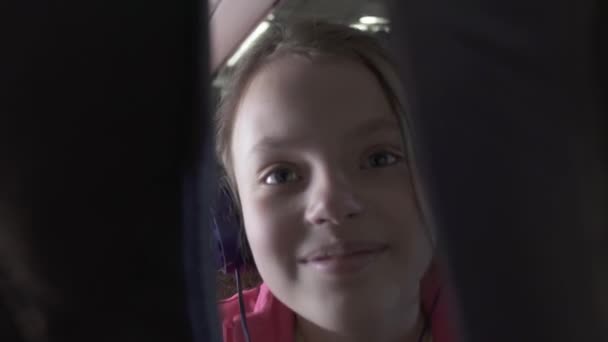 Vrolijke tienermeisje luistert naar muziek op de hoofdtelefoon in de cabine van het vliegtuig onderweg stock footage video — Stockvideo